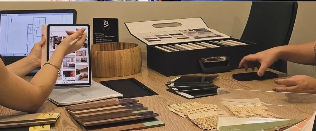 Mesa de reunião com amostras de madeira, tecidos e catálogo de acabamentos
